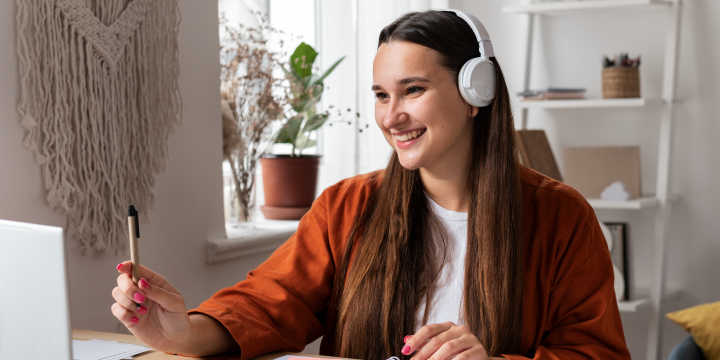Mujer jóven con audifonos sonriendo en una teleconferencia